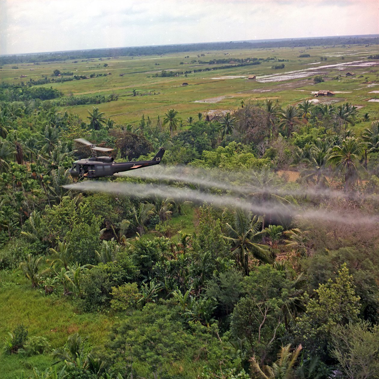 En UH-1D helikopter fra 336th Aviation Company sprøjter et afløvningsmiddel på et tæt jungleområde i Mekong-deltaet, 26. juli 1969 af American Photographer