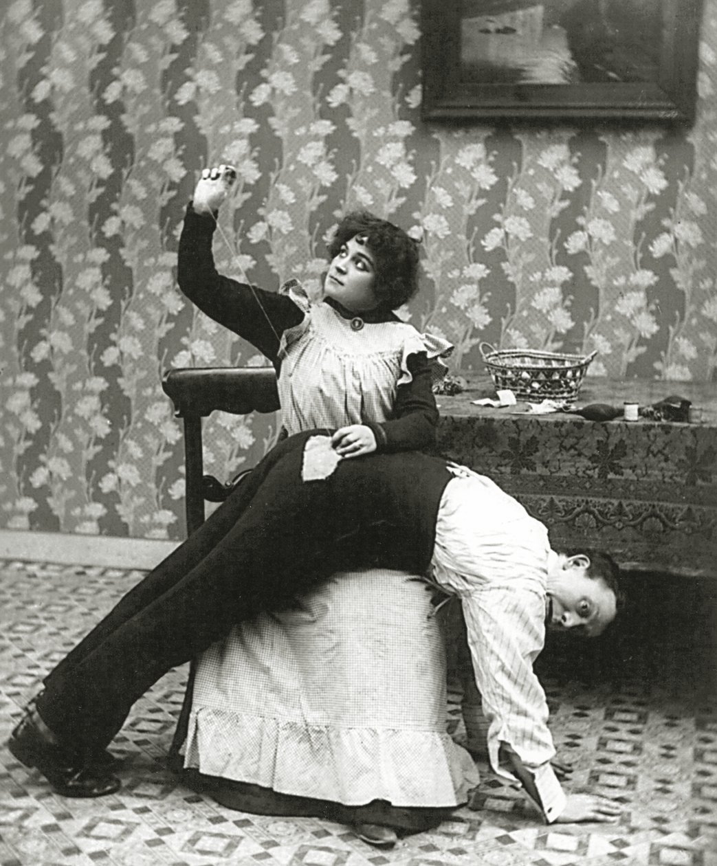 Kvinde syr en flænge på en mands bukser, ca. 1895 af American Photographer