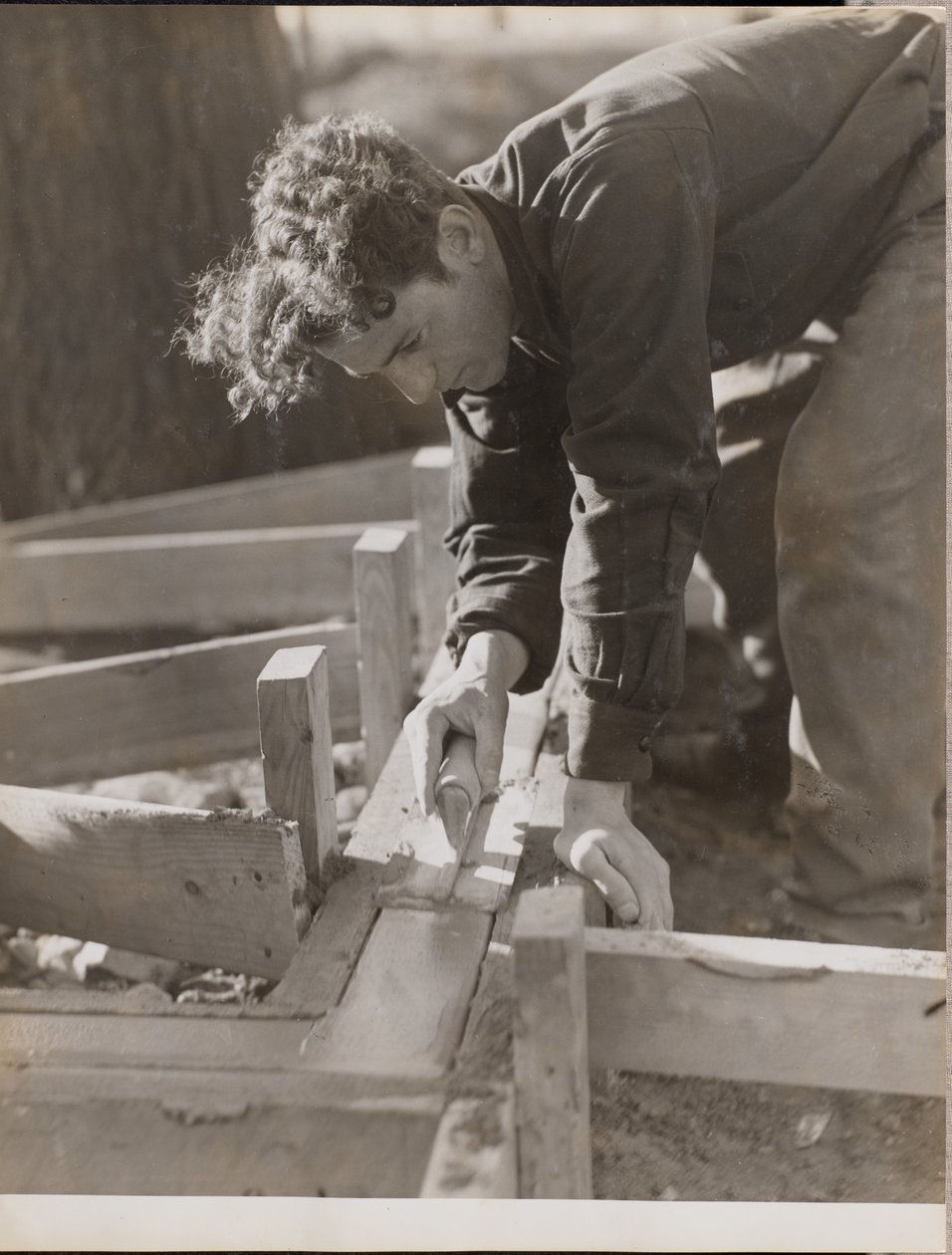 [Murer glatter cement, mens han støber et fundament]. af Arnold Eagle