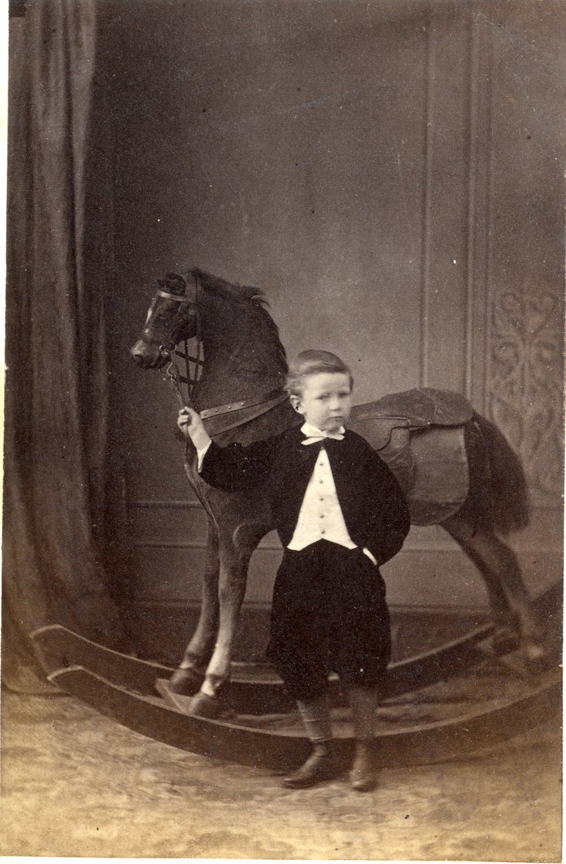 Dreng stående og holder tøjler af en gyngehest, 1860
