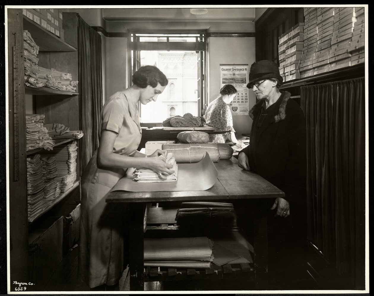 Ung kvinde pakker stofmaterialer ind, som en hjemmearbejder kan tage med, hos New York Association for the Blind, 111 East 59th Street, New York, 1931 (sølv gelatinetryk) af Byron Company