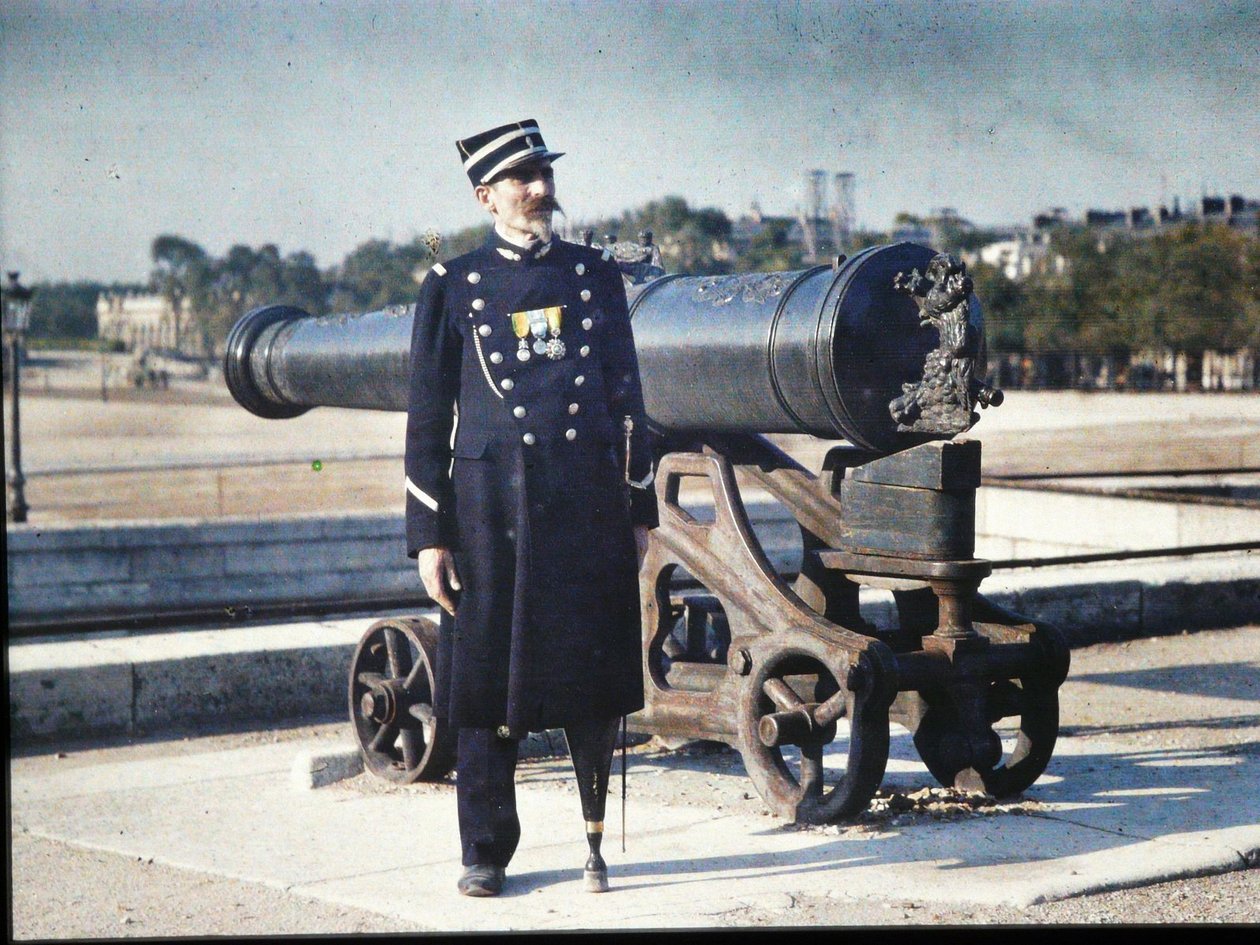 En soldat i uniform med tre medaljer står ved siden af en kanon i Paris, 1918 (autokrom) af Jules Gervais Courtellemont