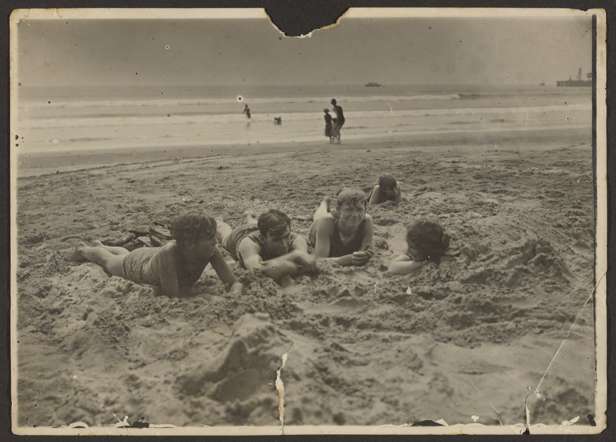 [Børn, der ligger i sandet på stranden] af Louis Fleckenstein