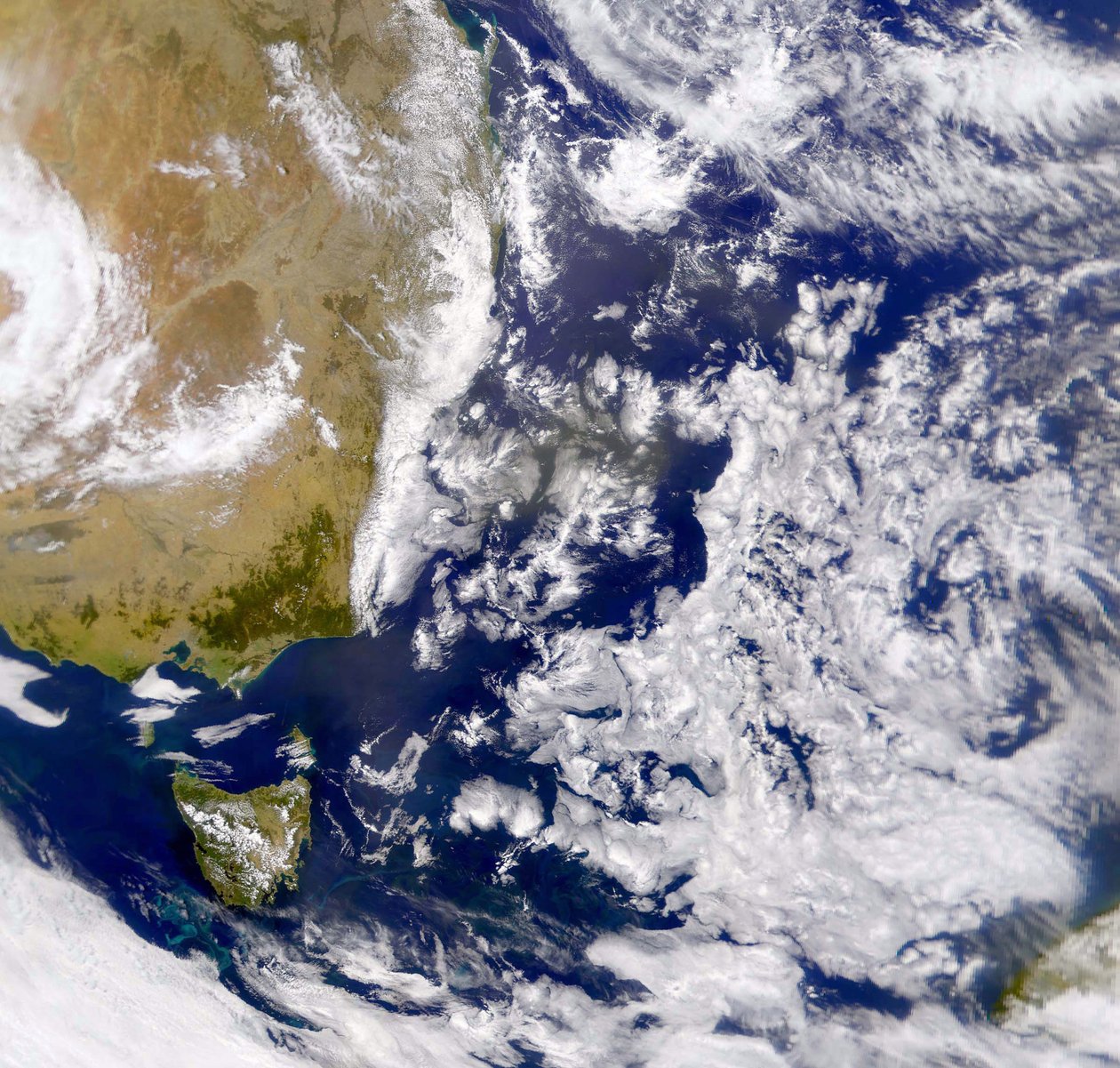 Satellitfoto af Tasmanhavet delvist dækket af skyer. Til venstre er en del af Australien med Tasmanien under sig. NASA. Videnskab af National Aeronautics and Space Administration National Aeronautics and Space Administration