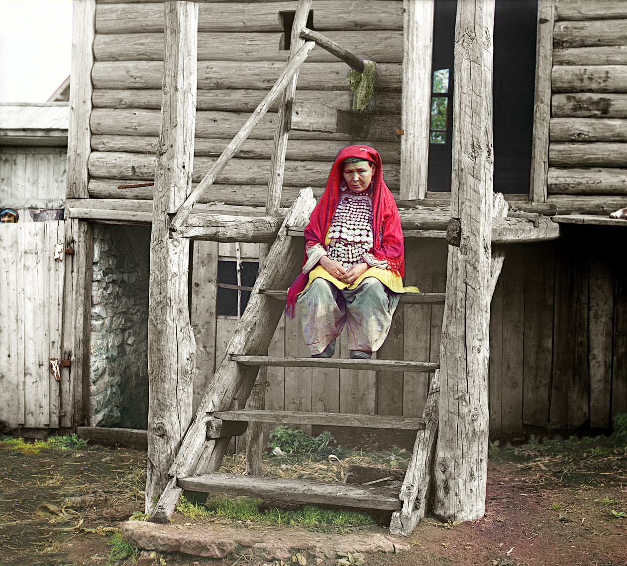 Basjkirisk kvinde i folkedragt siddende på trappen i sit træhus, Uralbjergene, Det Russiske Rige, 1910 af Sergey Prokudin Gorsky