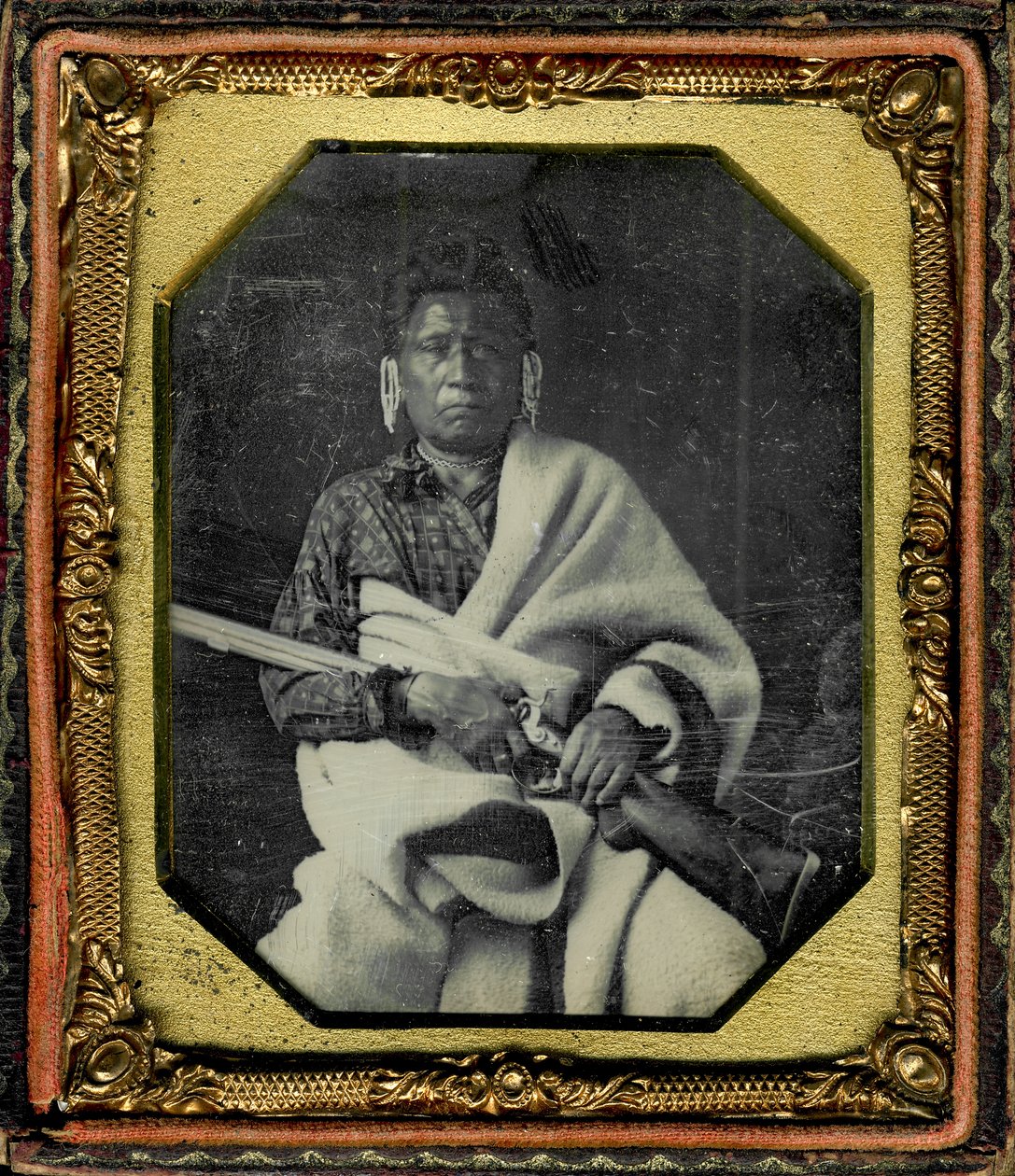 Portræt af Nacheninga [No Heart of Fear], Iowa. Nacheninga holder en pistol i hænderne og er svøbt i et tykt tæppe. af Thomas M. Easterly