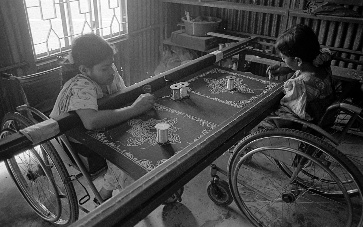 To fysisk udfordrede piger beskæftiger sig med broderi på tøjet på Center for Rehabilitering af Lammede, CRP i Savar, Dhaka, Bangladesh. 2005. af Unbekannt Unbekannt